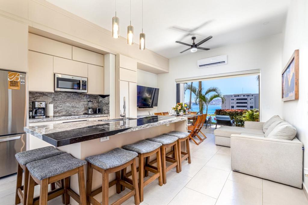 a kitchen and living room with a bar with stools at Beachfront luxury Condo w Pool in Cabo San Lucas