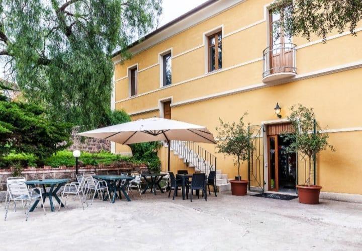 un patio con tavoli, sedie e un ombrellone di La Piazzetta Affittacamere a Ghilarza