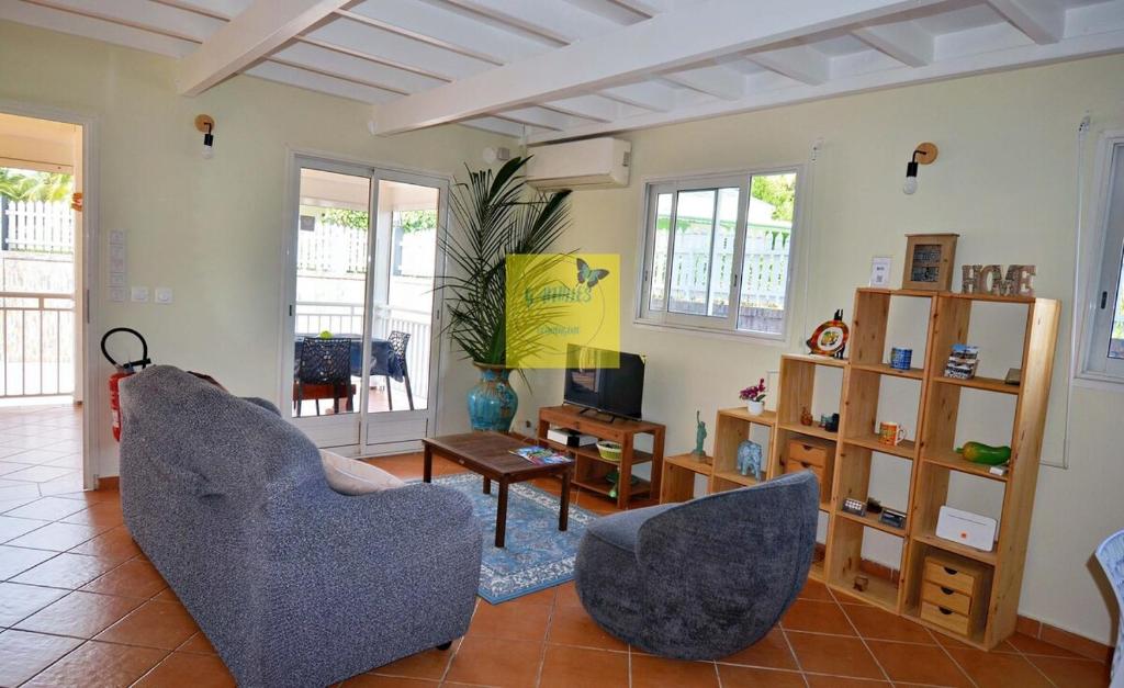 a living room with two chairs and a television at Dom pension in Baie-Mahault