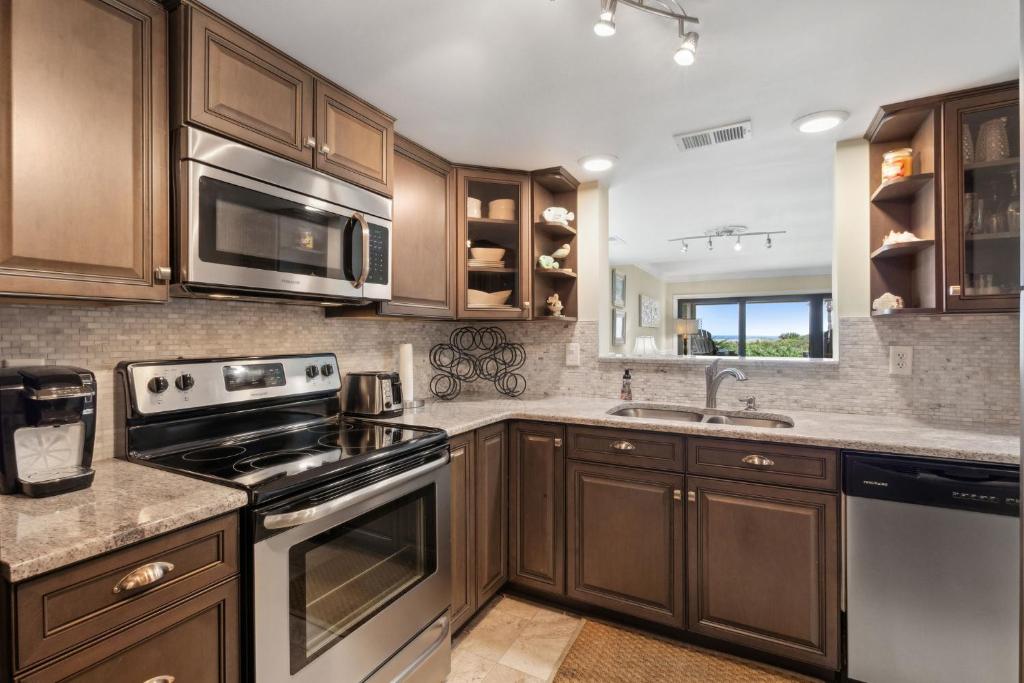 a kitchen with wooden cabinets and stainless steel appliances at Beautiful Corner Oceanfront 2-bedroom, 2 bath Condo in Amelia Surf & Racquet in Amelia Island