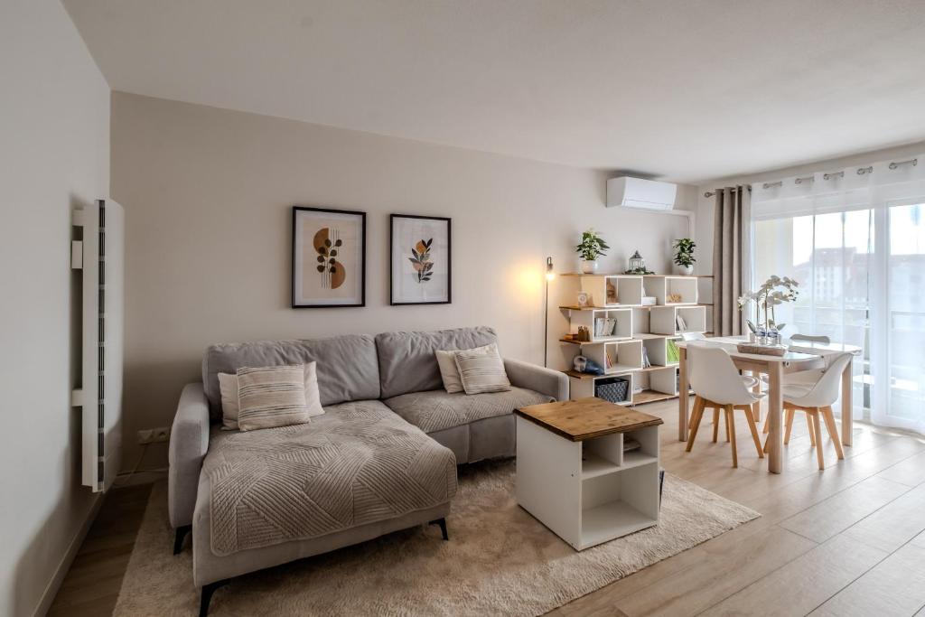 a living room with a couch and a table at La Résidence Fleurie, vue sur le Lac Léman in Thonon-les-Bains