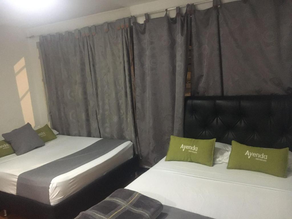 Estación El SaltoにあるHotel Boutique Bogotá Eliteのカーテン付きの客室で、ツインベッド2台が備わります。