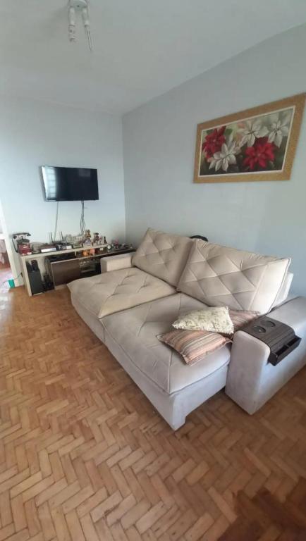 a living room with a white couch and a flat screen tv at Casa do Kazu in Águas da Prata