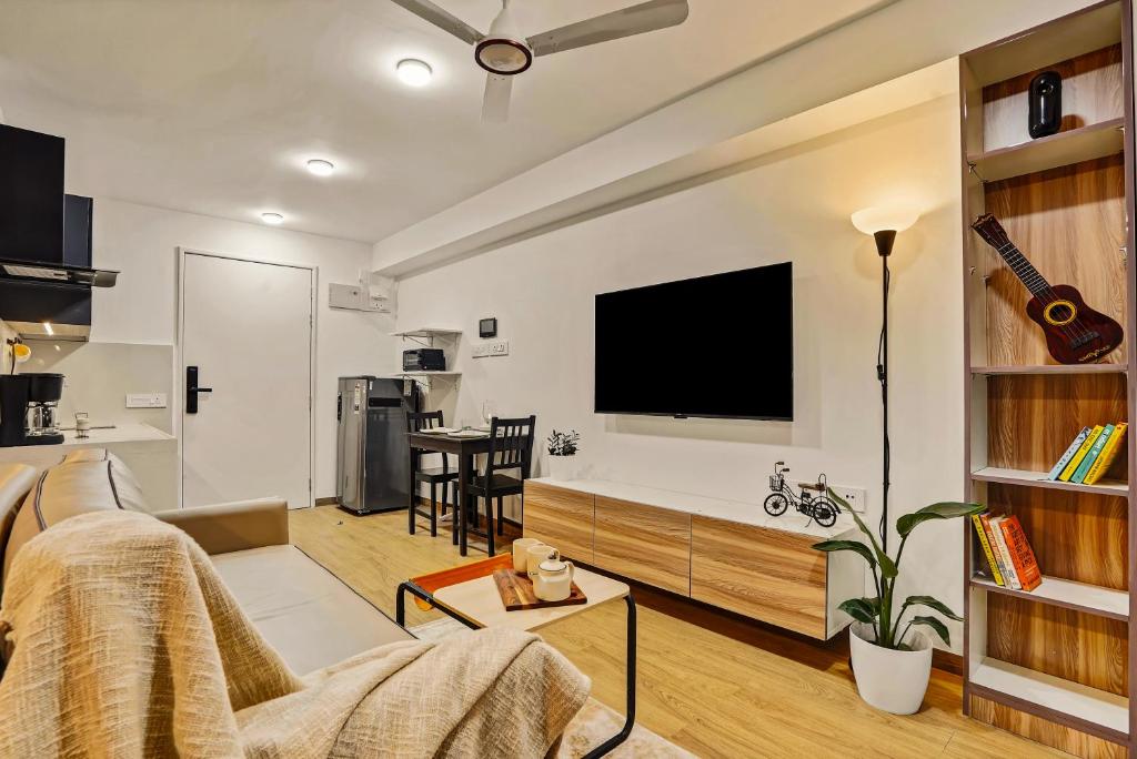 a living room with a couch and a flat screen tv at Orchid 001Airport view55 TVCoffee maker in Pune
