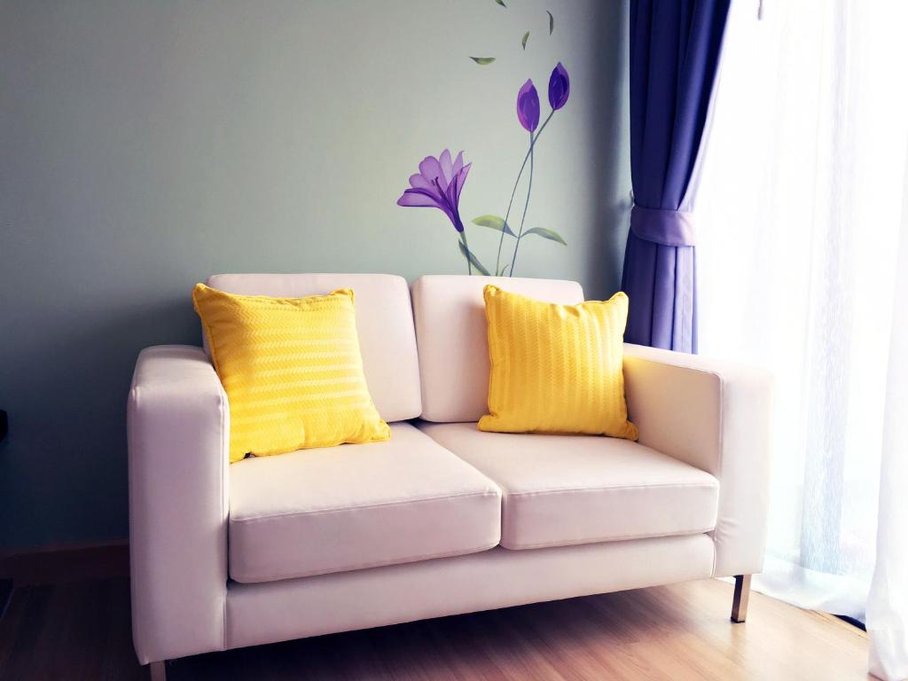 a white couch with two yellow pillows in a room at Happy Place Official in Nai Yang Beach