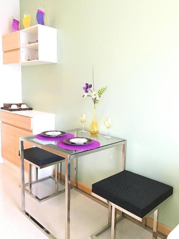 a glass table with two chairs and a vase with flowers at Happy Place Official in Nai Yang Beach