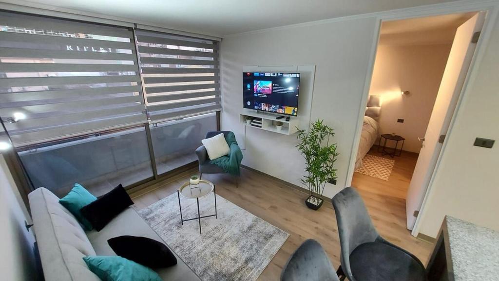 a living room with a couch and a tv at Departamento céntrico con estacionamiento in Concepción