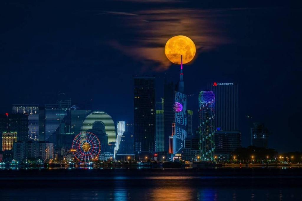 a full moon rising over a city skyline at night at Moonlight Apart-Hotel Batumi in Batumi