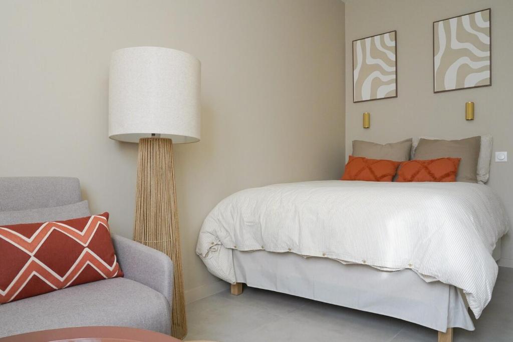 ein Schlafzimmer mit einem Bett, einer Lampe und einem Stuhl in der Unterkunft Le Fleury in Fontenay-le-Fleury