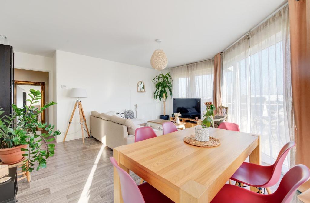 ein Wohnzimmer mit einem Holztisch und rosa Stühlen in der Unterkunft Appartement Cocooning in Tours