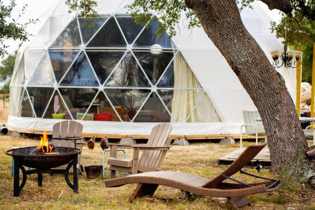 a tent with a table and chairs and a campfire at The Dome in Cloptins Crossing