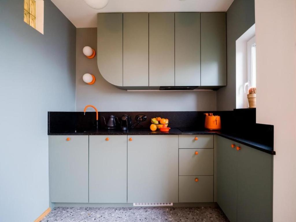 a kitchen with white cabinets and black counter tops at Orange and Towers Apartment in Wrocław