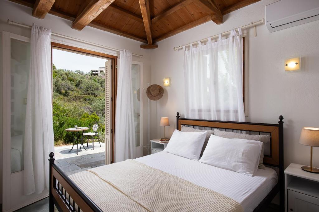 a bedroom with a bed and a large window at Lithea Villas and Studios by the Sea in Aghios Petros Alonissos
