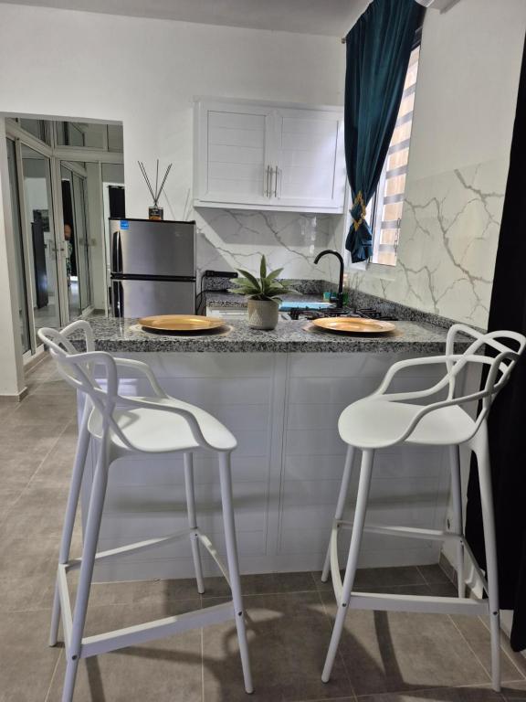 a kitchen with two white chairs and a counter at OMY Apartments Nagua 1B in Nagua
