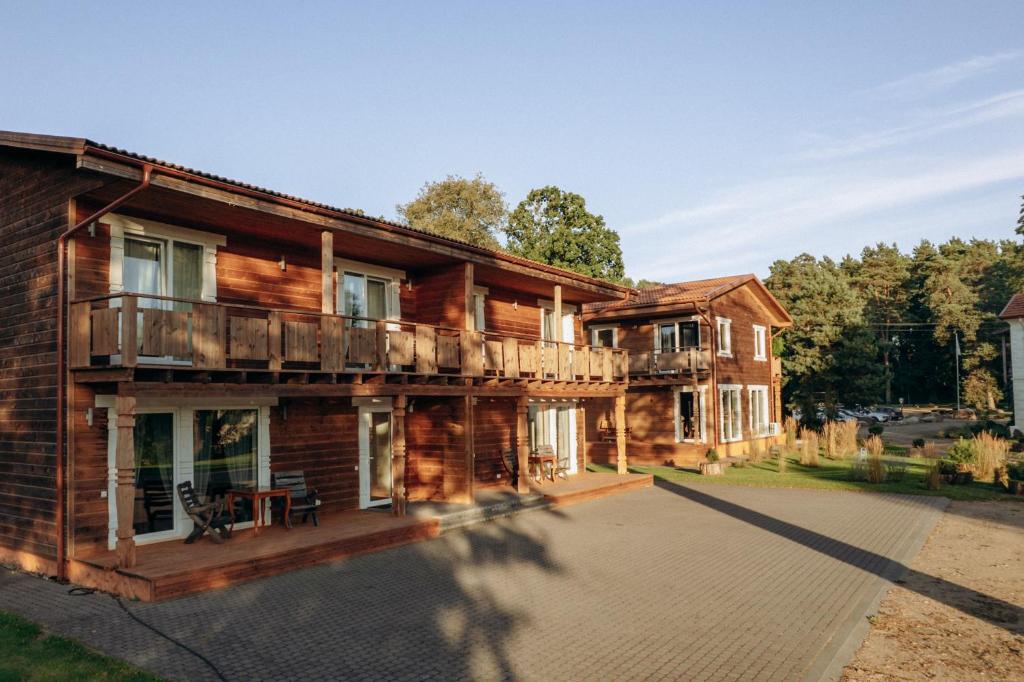 a log house with a porch and a balcony at Pauliankos slėnis 1 in Krakiai