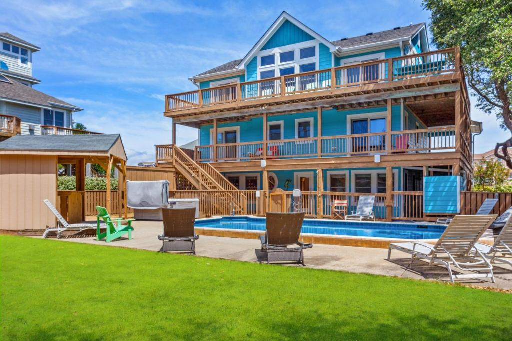 a house with a swimming pool and lawn at 2070 - Sol Mates in Duck