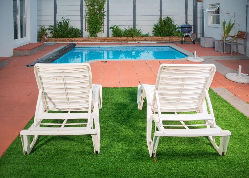 two white chairs sitting on the grass near a pool at Mindful Escape Cottage in Heathfield