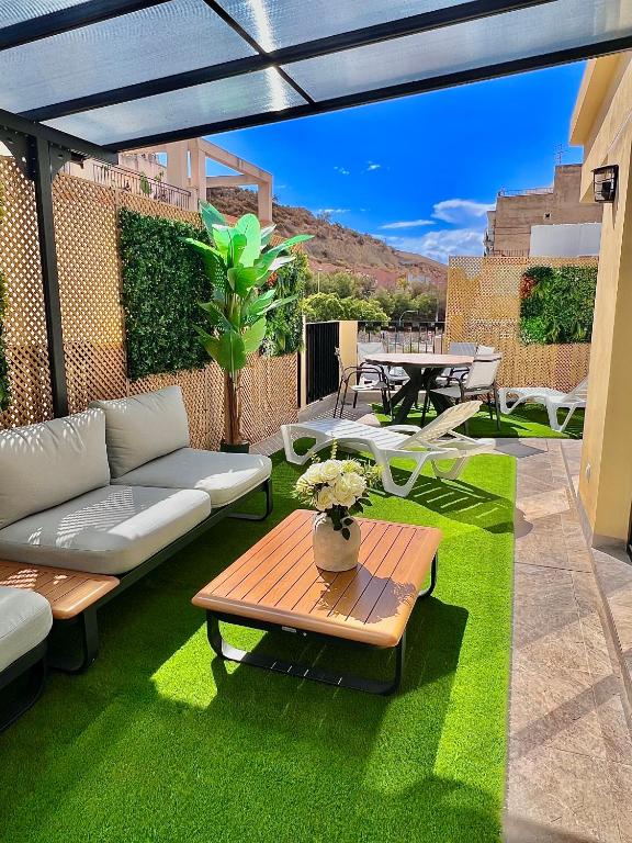 a patio with a couch and a table on grass at La huerta centro in Alicante