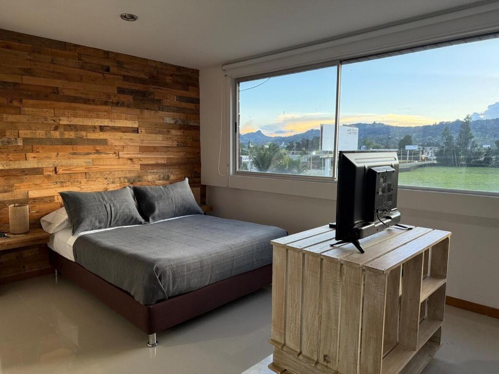 a bedroom with a bed and a tv and a window at Countryside apartment in Rionegro
