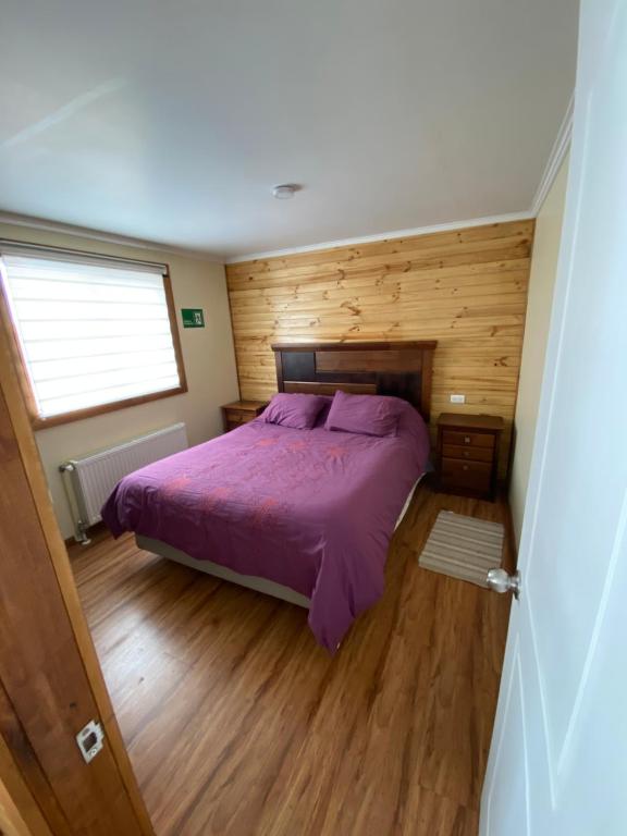 a bedroom with a purple bed and a window at Departamento Marve in Puerto Natales