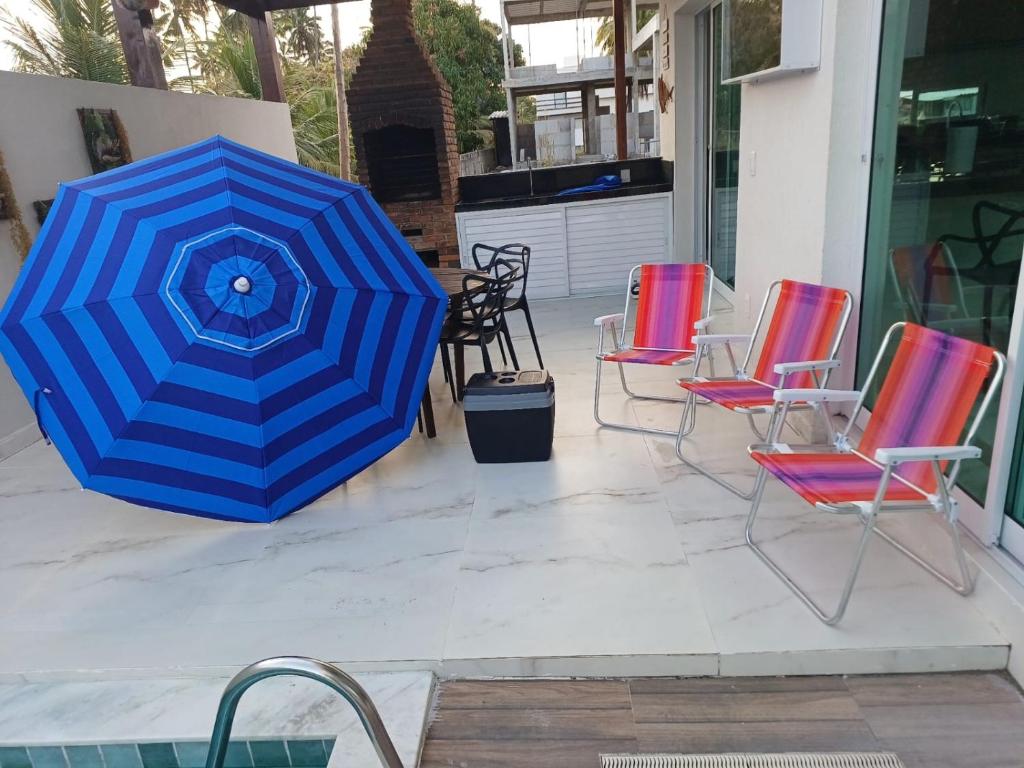 a group of chairs and an umbrella on a patio at Casa Estrela do Mar in Maragogi