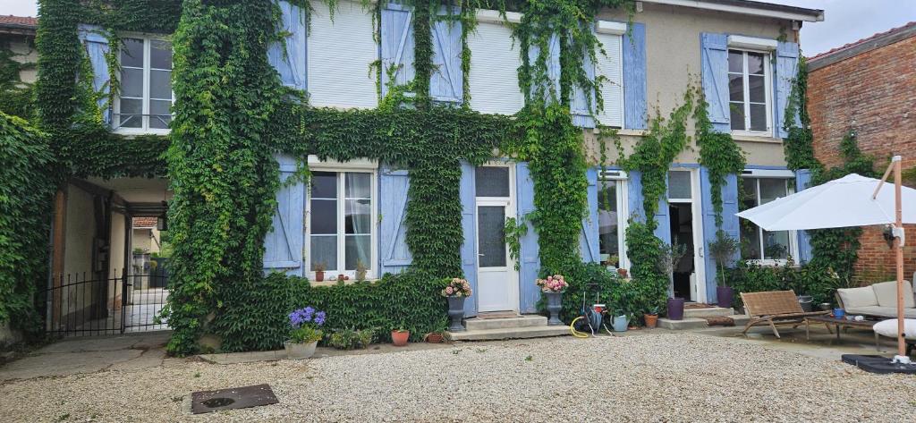 a house covered in ivy with a table and an umbrella at Chez Mary in Larzicourt