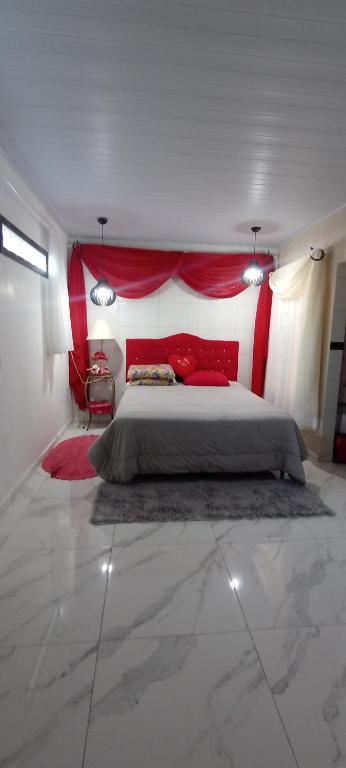 a bedroom with a large bed with red pillows at Ksl refúgio dos pássaros in Araquari