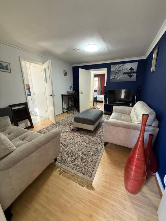 una sala de estar con 2 sofás y un jarrón rojo en Modern Wembley Apartment Walk to Stadium & Arena, en Londres