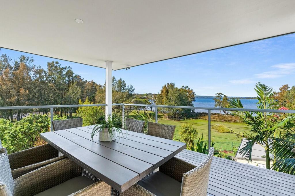 a table and chairs on a balcony with a view of the ocean at Killarney at Old Erowal Bay in Erowal Bay