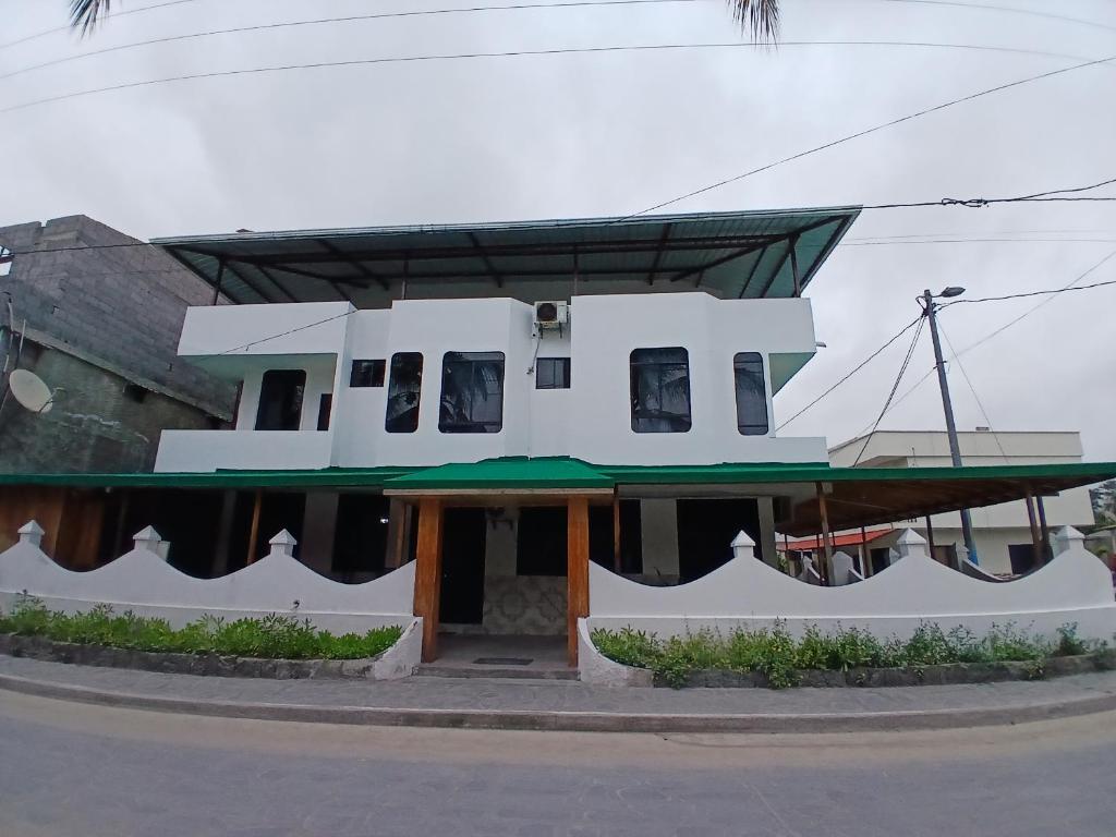 a white house with a green roof at Hostal Brisas Del Mar in Puerto Villamil