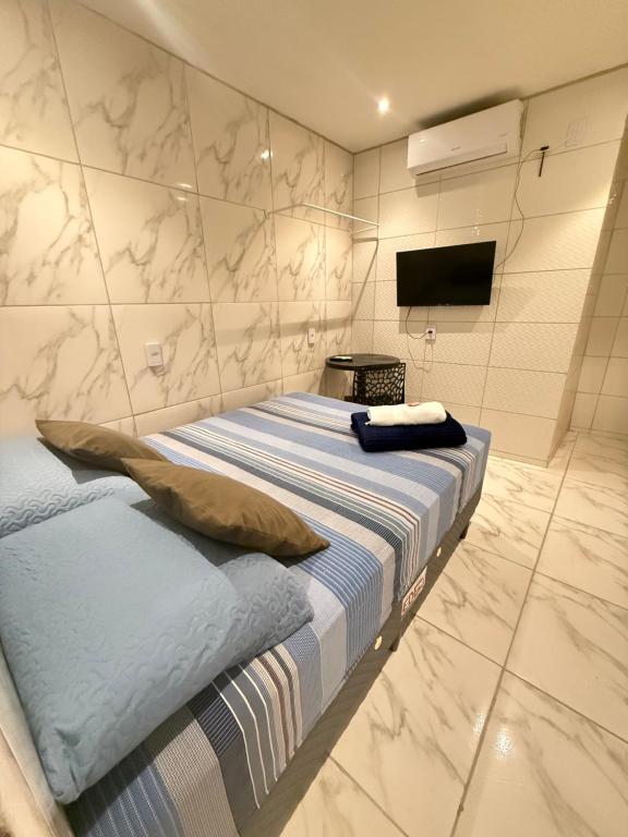 a bedroom with a bed and a tv on a wall at Cantinho aconchegante - Quarto 05 AR-condicionado in Bayeux