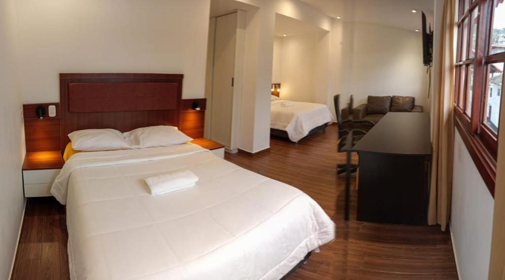 a hotel room with two beds and a desk at Hoteles Silva Inn in Cajamarca