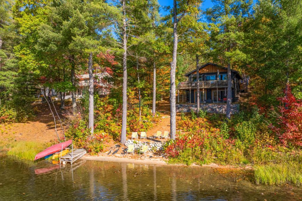 a house on the shore of a lake with a bench at Deck and Fire Pit Beachfront Home in Gaylord! in Gaylord