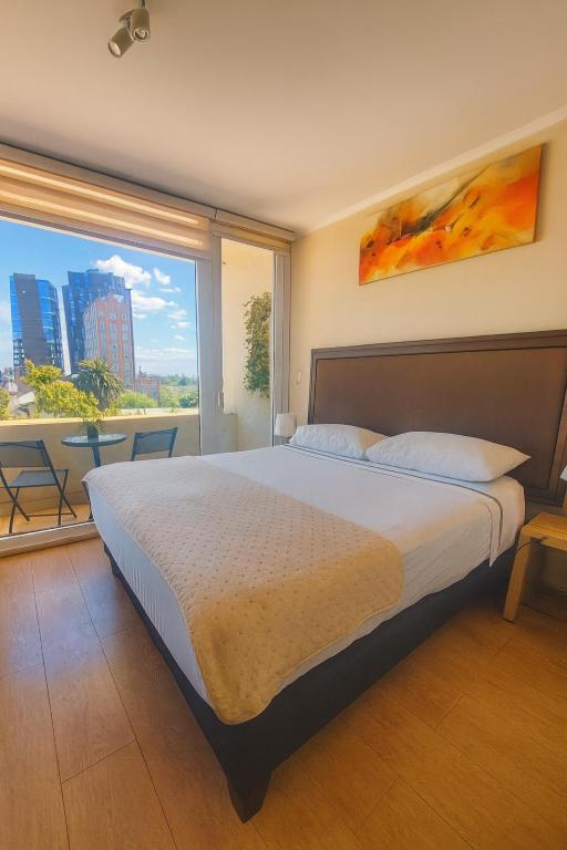 a bedroom with a large bed and a large window at DEPARTAMENTO PREMIUM en Chillán Centro, full equipado, cómodo, con estacionamiento, factura para empresas, wifi de alta velocidad in Chillán