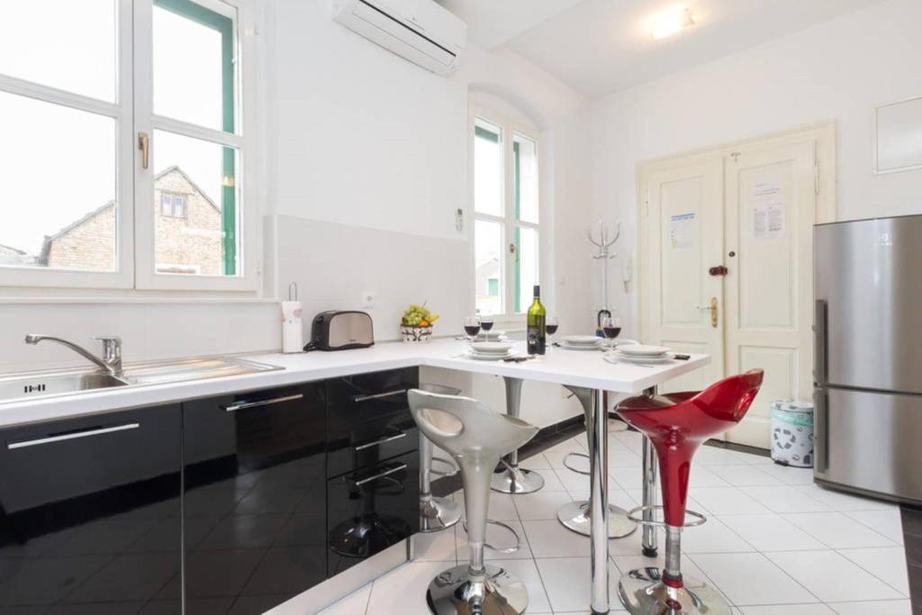 a kitchen with a large white counter and red stools at Apartment Central Old town in Split