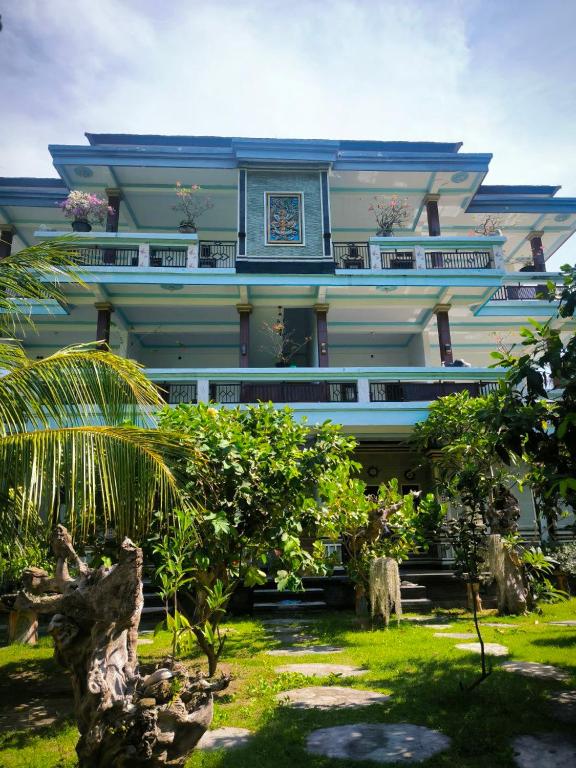 a large blue building with a palm tree in front of it at Pondok Segara Guesthouse in Padangbai