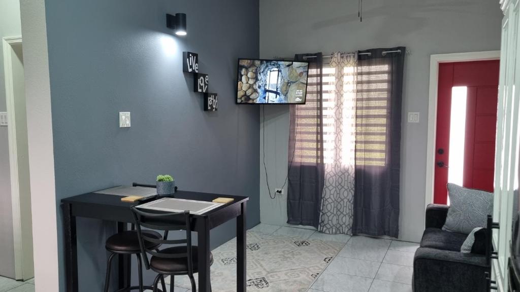 Una sala de estar con una mesa y un televisor en la pared. en Rest Easy at Cunningham Suites, en Ottleyʼs Village