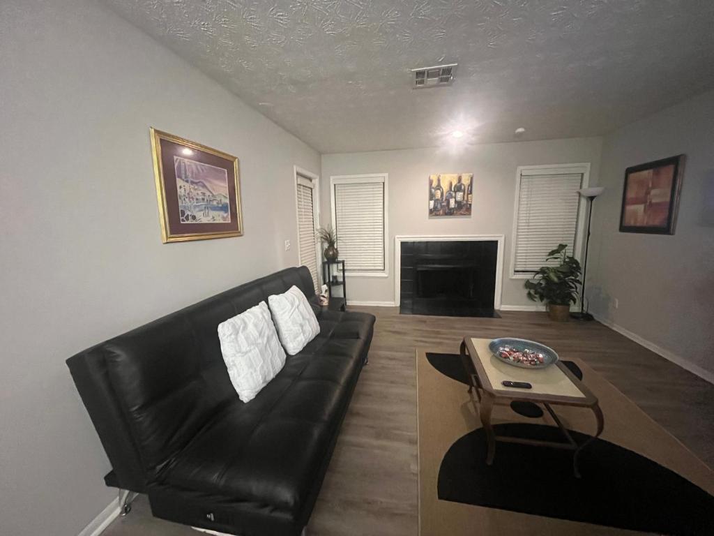 a living room with a black leather couch and a table at Cozy Vinings Hideaway in Atlanta