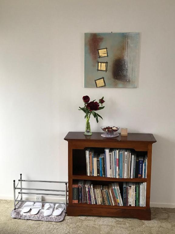 a book shelf with a vase of flowers on it at The Bivvy at Hutt Central in Lower Hutt