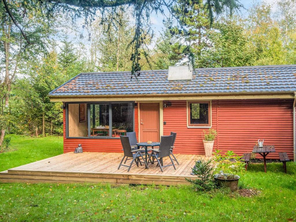 Casa roja con terraza con mesa y sillas en 4 star holiday home in Ry, en Ry