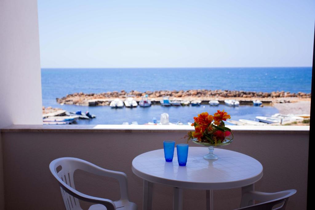 a table with a vase of flowers and blue glasses at Ascoltando Il Mare in Lido Signorino