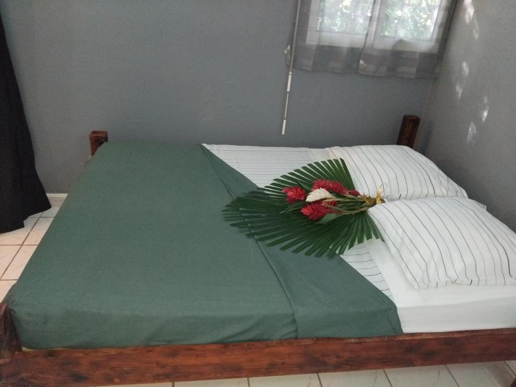 a bed with a green comforter with a flower on it at Résidence Belle Place Palmier in Saint-François