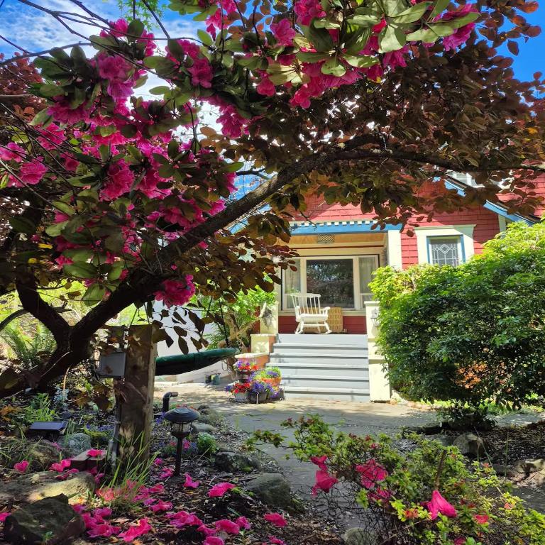 a house with pink flowers in front of it at Garden suite on Trinity St in Vancouver