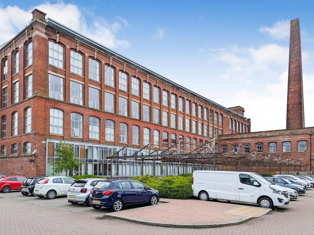 a large brick building with cars parked in front of it at Preston City Apartment in Preston