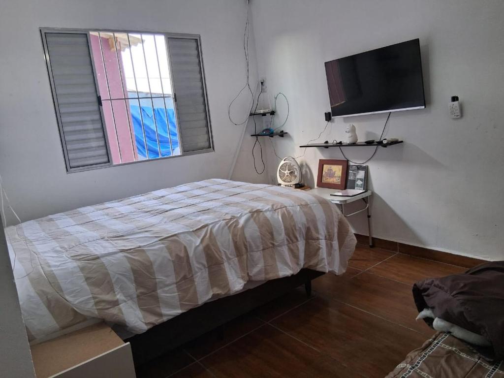 ein Schlafzimmer mit einem Bett und einem Flachbildfernseher in der Unterkunft Pé Na Areia in Ilha Comprida