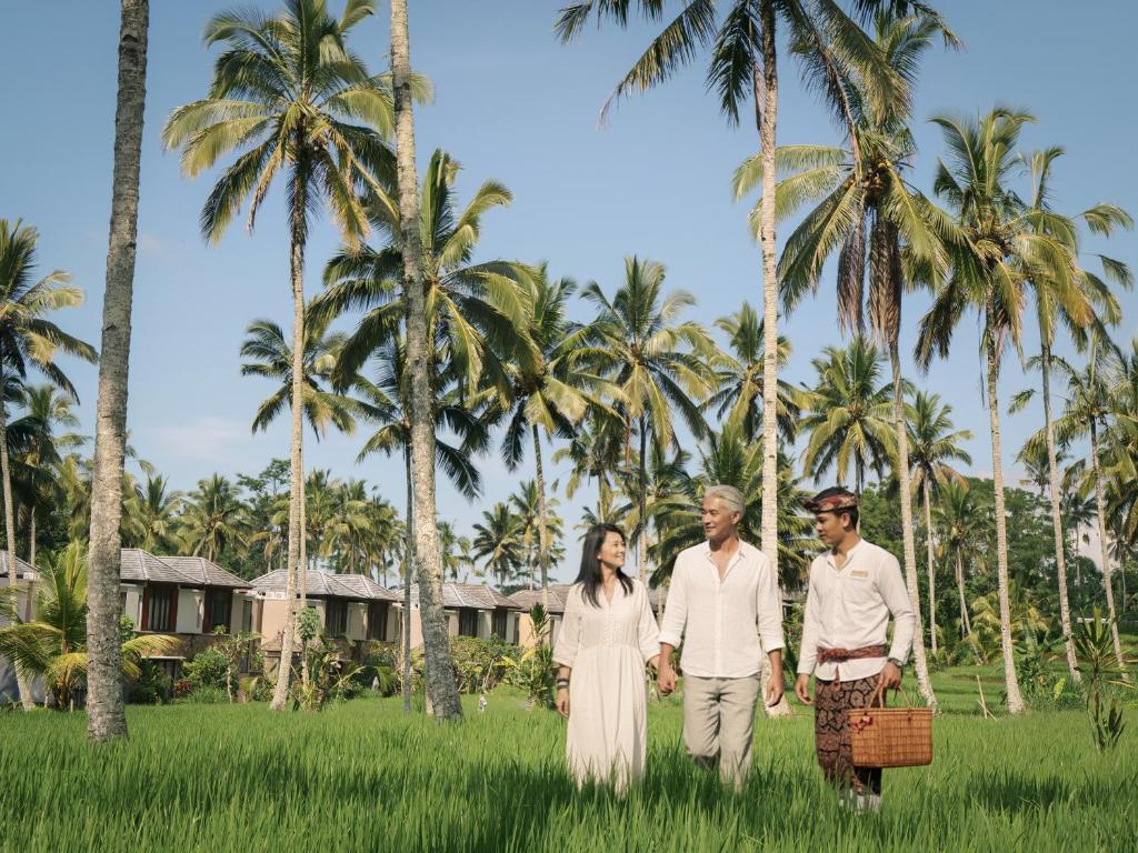 a couple walking through a field with palm trees at Khastana Hadi Tegallalang, Ubud in Tegalalang