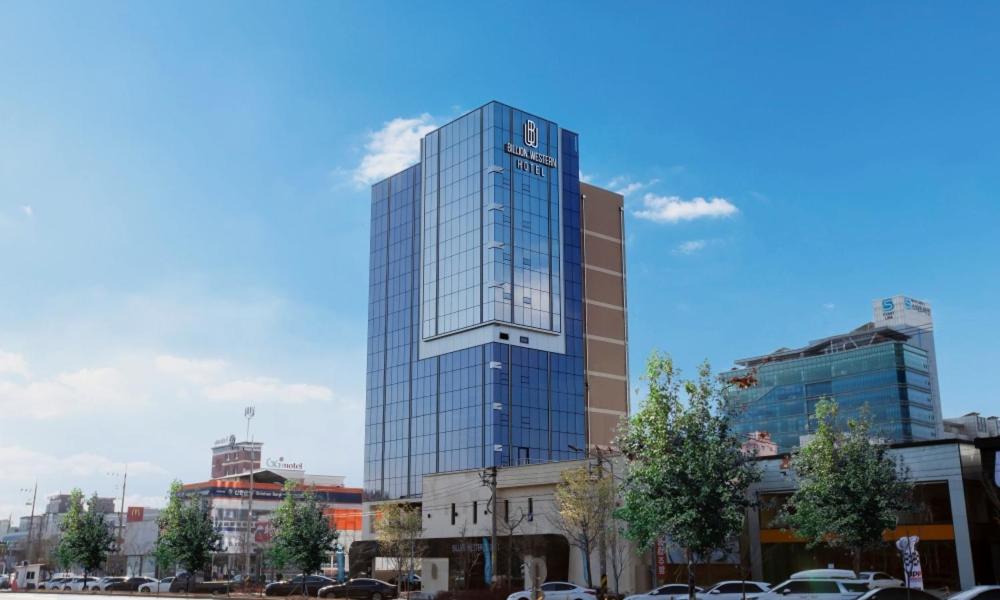 a tall glass building with a clock on it at Daegu Billion Western Hotel in Daegu