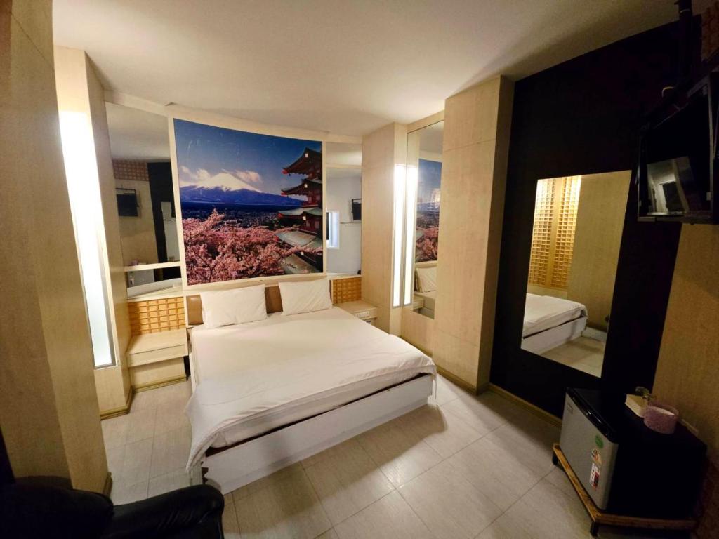 a bedroom with a bed and a painting on the wall at Save Hotel เซฟ โฮเทล in Chon Buri