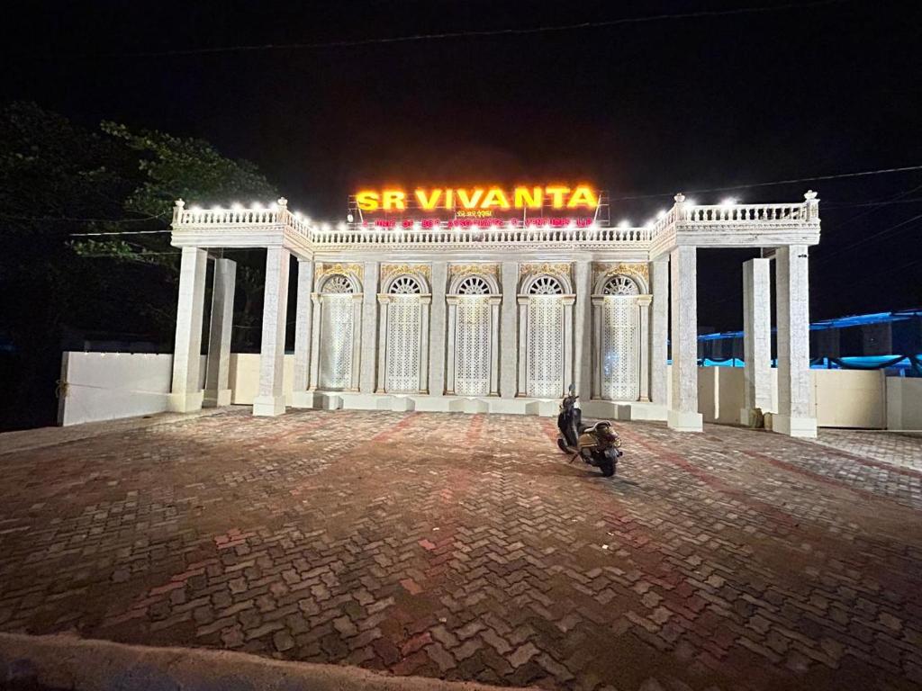 un grand bâtiment blanc avec une enseigne lumineuse dans l'établissement SR Vivanta, à Brahmapur