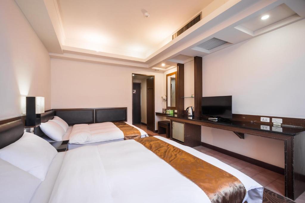 a hotel room with three beds and a television at Twinstar Hotel in Taichung